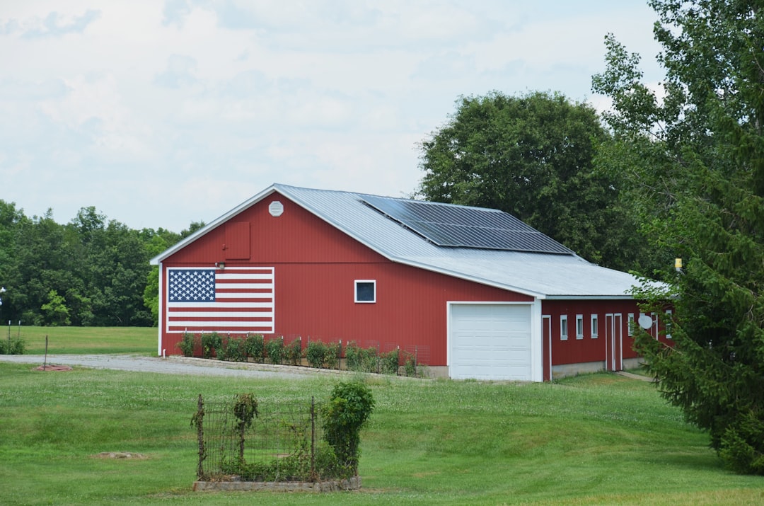Red barn with american flag and solar panels on roof.