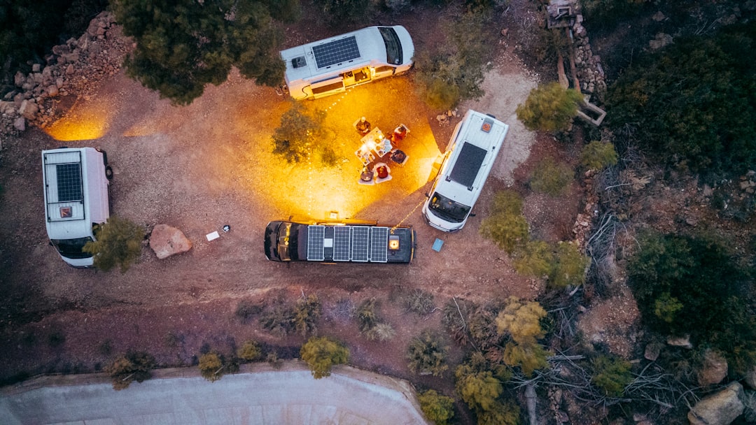 Five camper vans gathered around a campfire at dusk.
