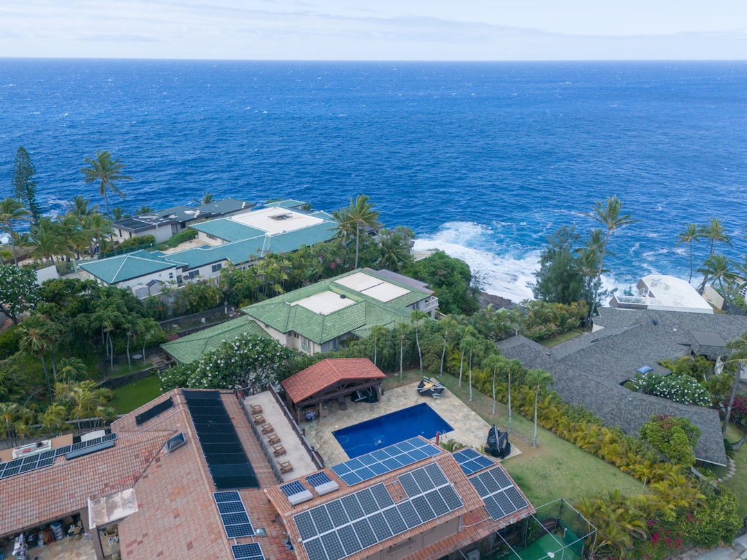 Tropical homes with solar panels and pools overlook the ocean.